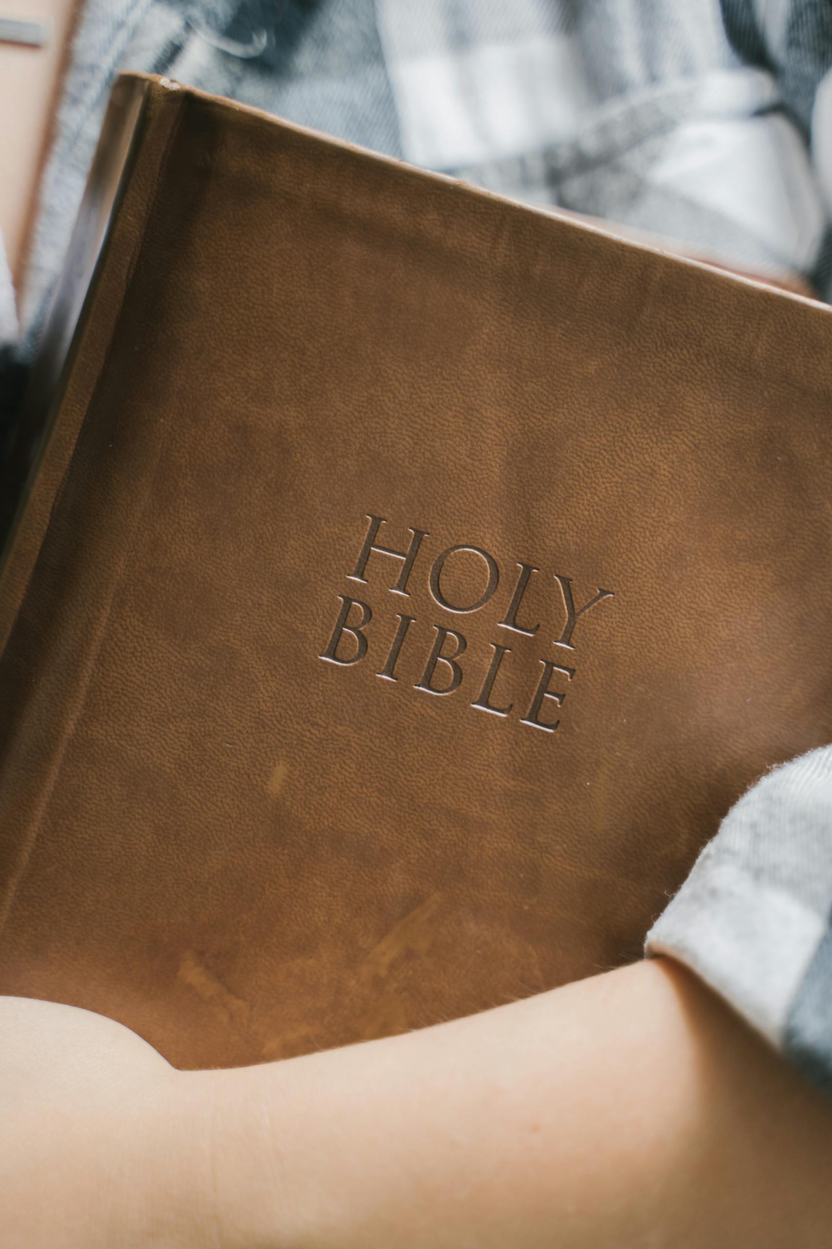 Close-up of hands praying on a Holy Bible, symbolizing faith and spirituality.